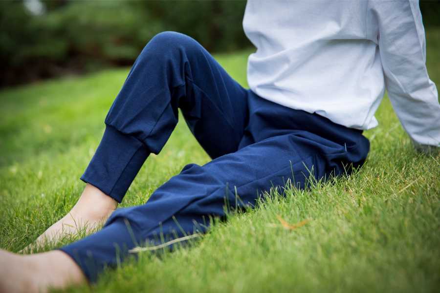 Chlapec sedí na trávníku s pokrčenou nohou, není vidět hlava